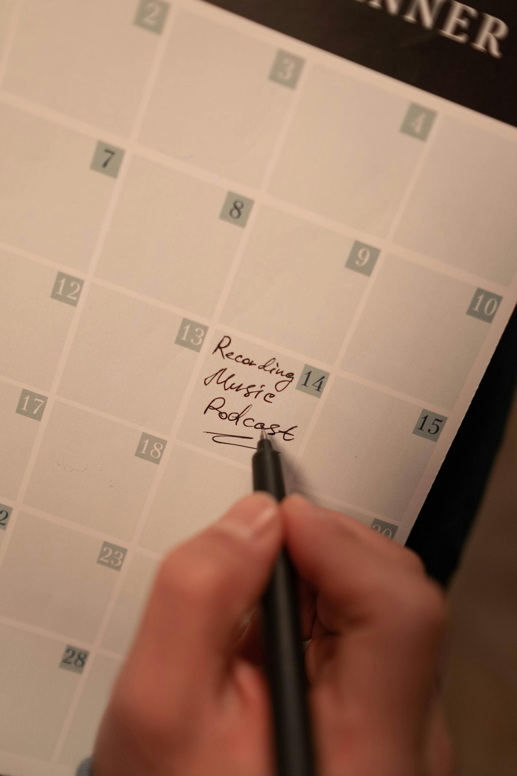 Close-up of a hand writing podcast recording date on a calendar. Ideal for content planning concepts. Goal Setting Worksheet