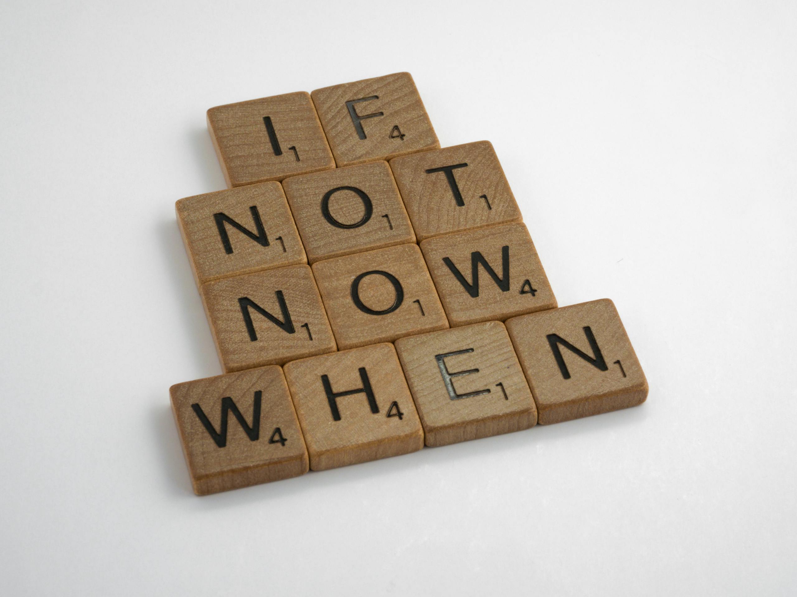 Overcome Procrastination Wooden letter tiles spelling 'If Not Now When' on a white background for inspiration.